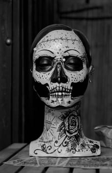 Close view of a female painted doll face with dark motifs.