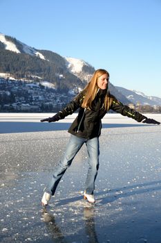 Pirouette of young woman figure skating at frozen lake of zell am see in austria