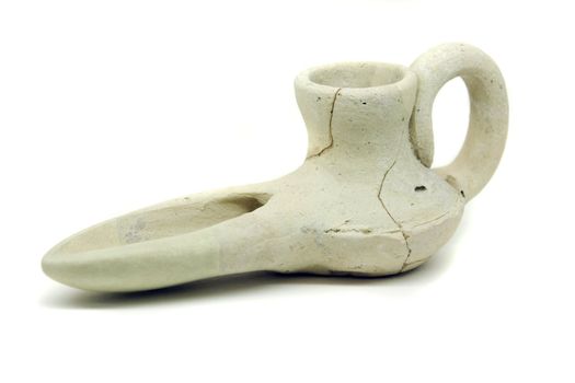 Close view of an ancient islamic oil lamp artifact on white background.