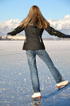 Pirouette of young woman figure skating at frozen lake of zell am see in austria