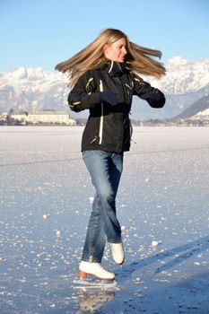 Pirouette of young woman figure skating at frozen lake of zell am see in austria