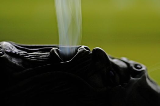 Close view of a smoking doll with smoke getting out of it's mouth.