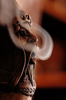 Closeup view of a smoking incense doll with smoke.