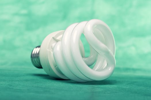 Close view of a curly light bulb on a green background.