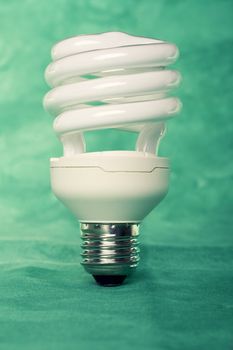 Close view of a curly light bulb on a green background.