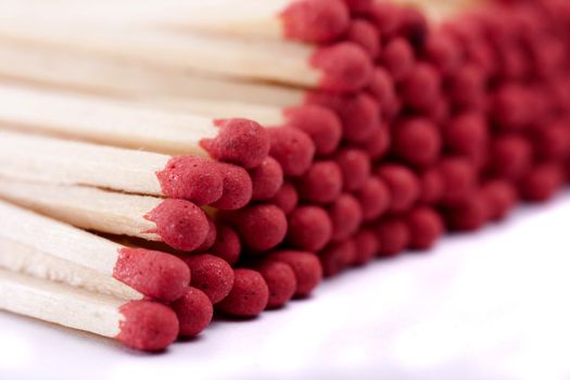 Close up view of a bunch of matches with red heads on a white background.