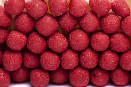 Close up view of a bunch of matches with red heads on a white background.
