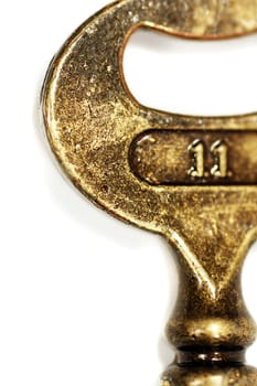 Macro view of an old golden key with the number 11 isolated on a white background.