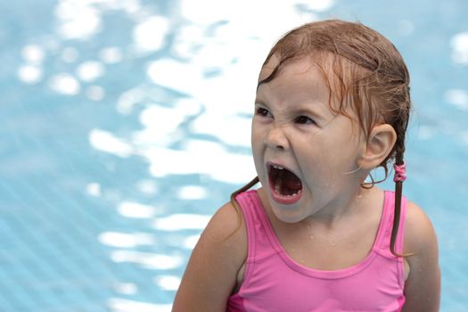 little girl in the pool opened her mouth wide