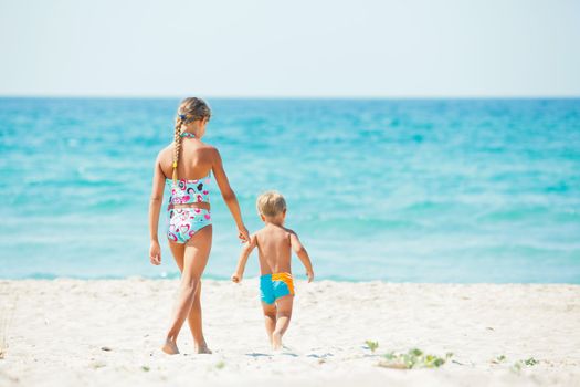 Young beautiful girl and boy playing happily at pretty beach