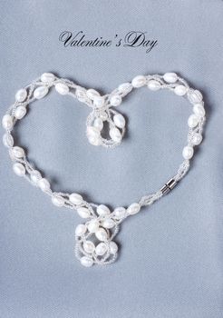Heart-shaped string with perals on a gray cloth