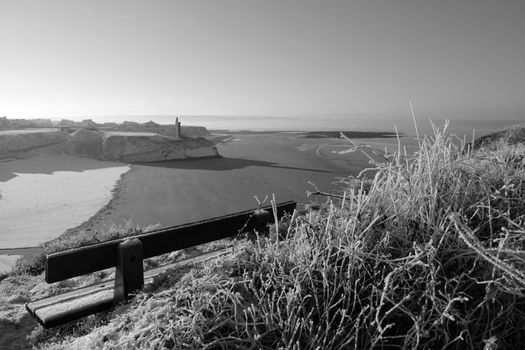 beach and ballybunion castle with a bench on a frosty snow covered winters day in black and white