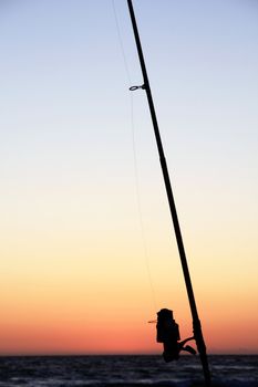 View of a fishing pole silhouette near the shoreline.