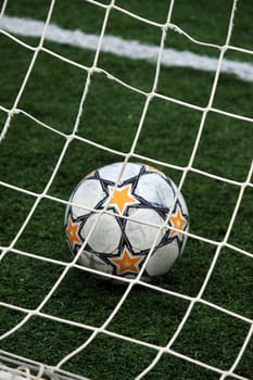 View of a soccer ball inside the goalpost on the grass.