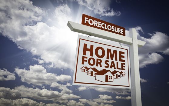 White Foreclosure Home For Sale Real Estate Sign Over Beautiful Clouds and Blue Sky.