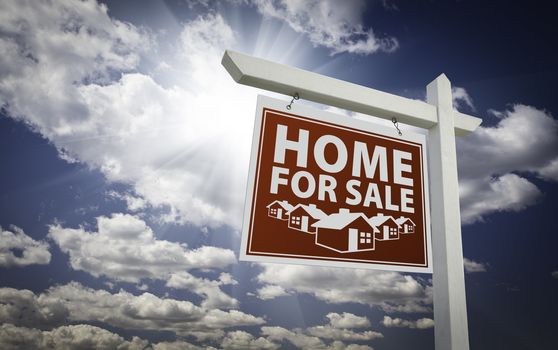 Red Home for Sale Real Estate Sign Over Beautiful Clouds and Blue Sky.