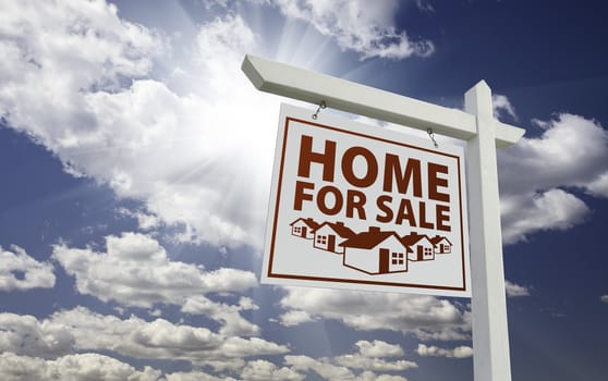 White Home For Sale Real Estate Sign Over Beautiful Clouds and Blue Sky.