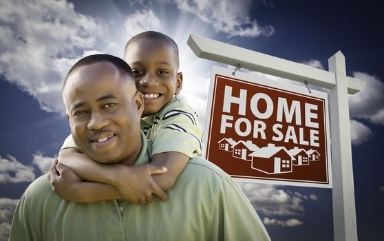 Happy African American Father with Son In Front of Home For Sale Real Estate Sign and Sky.
