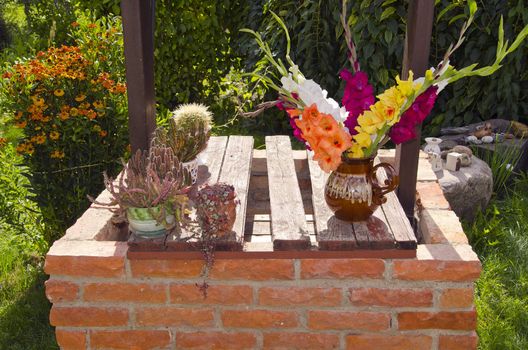 Cacti and multicolor flowers dapped in vase.