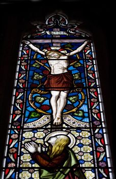 Beautiful stained glass window depicting Jesus on the crucifix with Mary at his feet