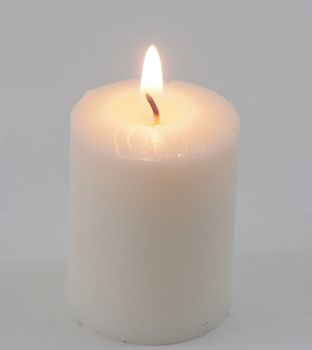 White candle with flame on white background