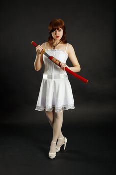A young girl stands on a black background with a sword