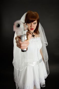 Young bride threatens us with a gun on black background