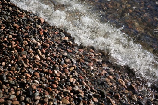 Wave and small stones at seashore