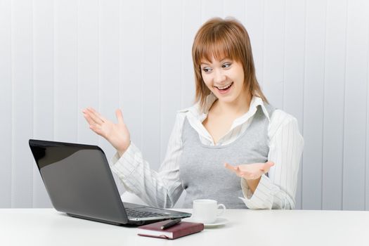 girl in office pleasantly surprised, looking at laptop
