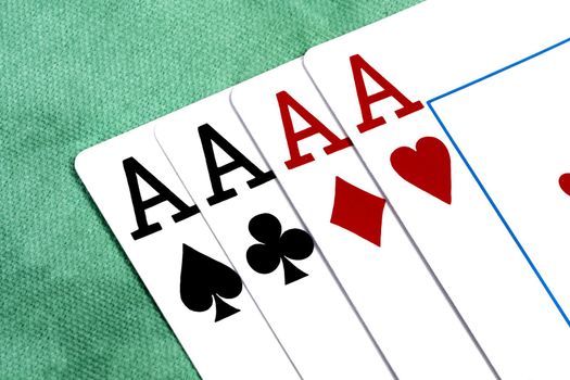 Close up view of four aces spread on a green cloth table.
