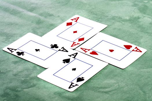 Close up view of a set of four aces spread on a green cloth table.