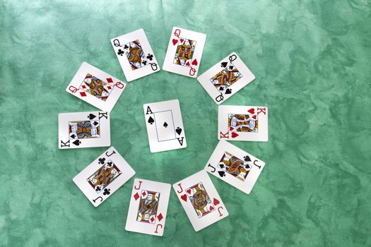 Close up view of a circle of playing cards spread on a green cloth table.