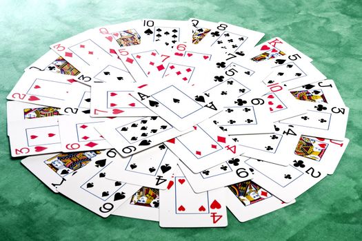 Close up view of a bunch cards spread on a green cloth table forming a circle.