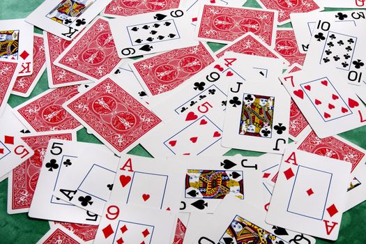 Close up view of a bunch of playing cards spread on a green cloth table.