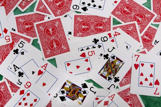 Close up view of a bunch of playing cards spread on a green cloth table.