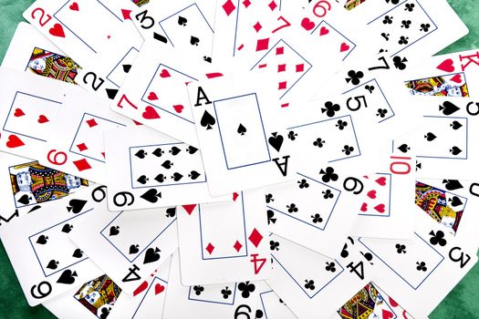 Close up view of a bunch cards spread on a green cloth table forming a circle.