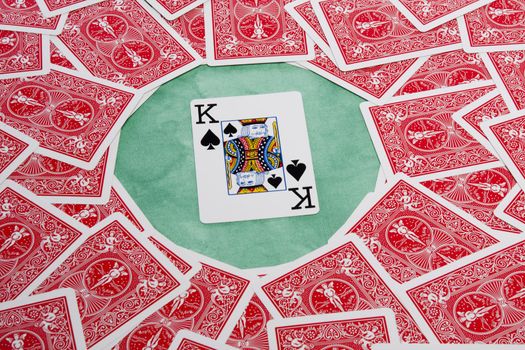 Close up view of a bunch of flipped playing cards spread on a green cloth table.