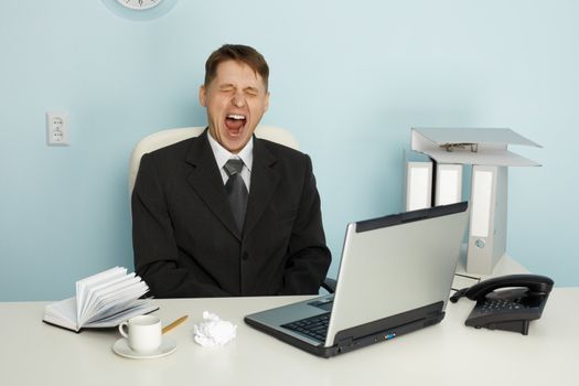 Businessman yawning from boredom and idleness in the office
