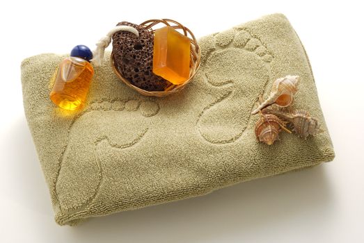 Beige foot SPA set with soap, pumice and shells on towel with footprints 