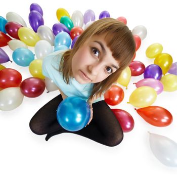 A young woman sitting on the floor among the colorful balloons