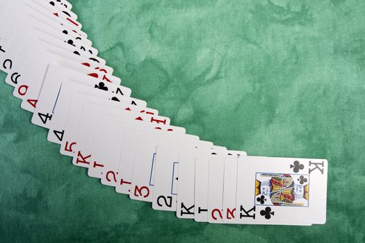 Close up view of a bunch cards spread on a green cloth table.