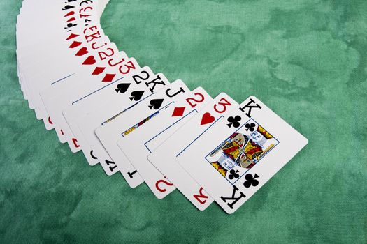 Close up view of a bunch cards spread on a green cloth table.
