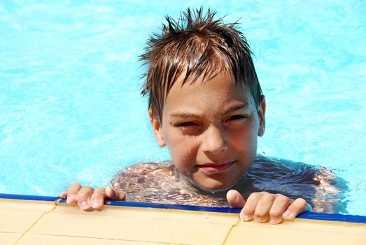 wet young smiling boy portrait in blue resort swimming pool