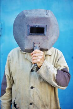 Builder - welder holding a old welding mask