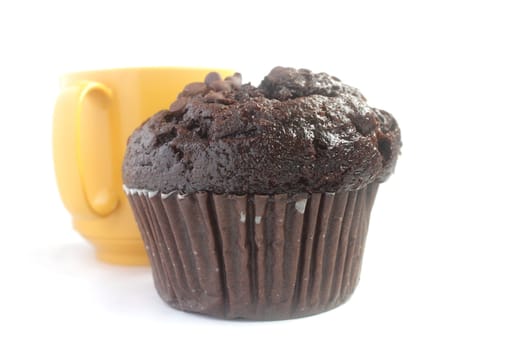 Chocolate muffin and a yellow cup of tea isolated on white background