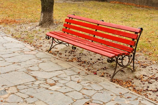 The old red wooden bench in the autumn park