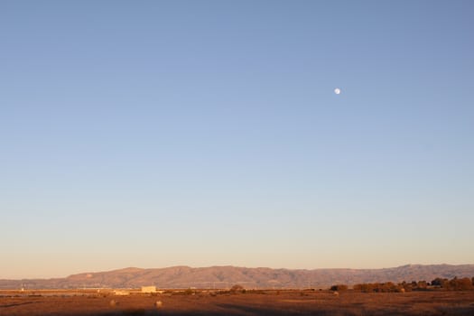 Evening lanscape with mountains on the horizon and the Moon