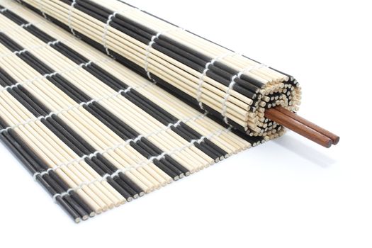 Half-rolled bamboo mat with pair of chopsticks on white background