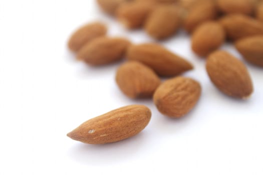 Group of almonds with single one in focus on white background