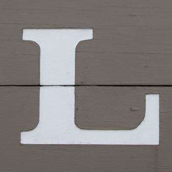White carved letter l on the wooden board